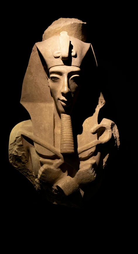 a statue of a pharaoh is lit up by a black background