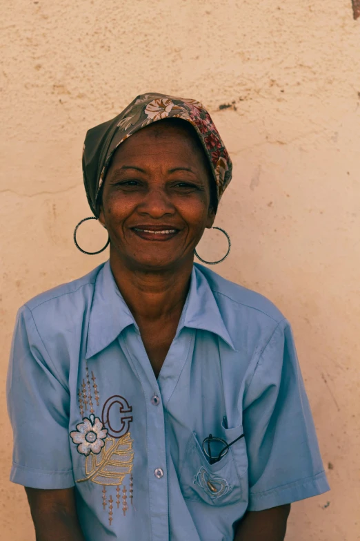 a smiling woman in blue wearing large circular earrings