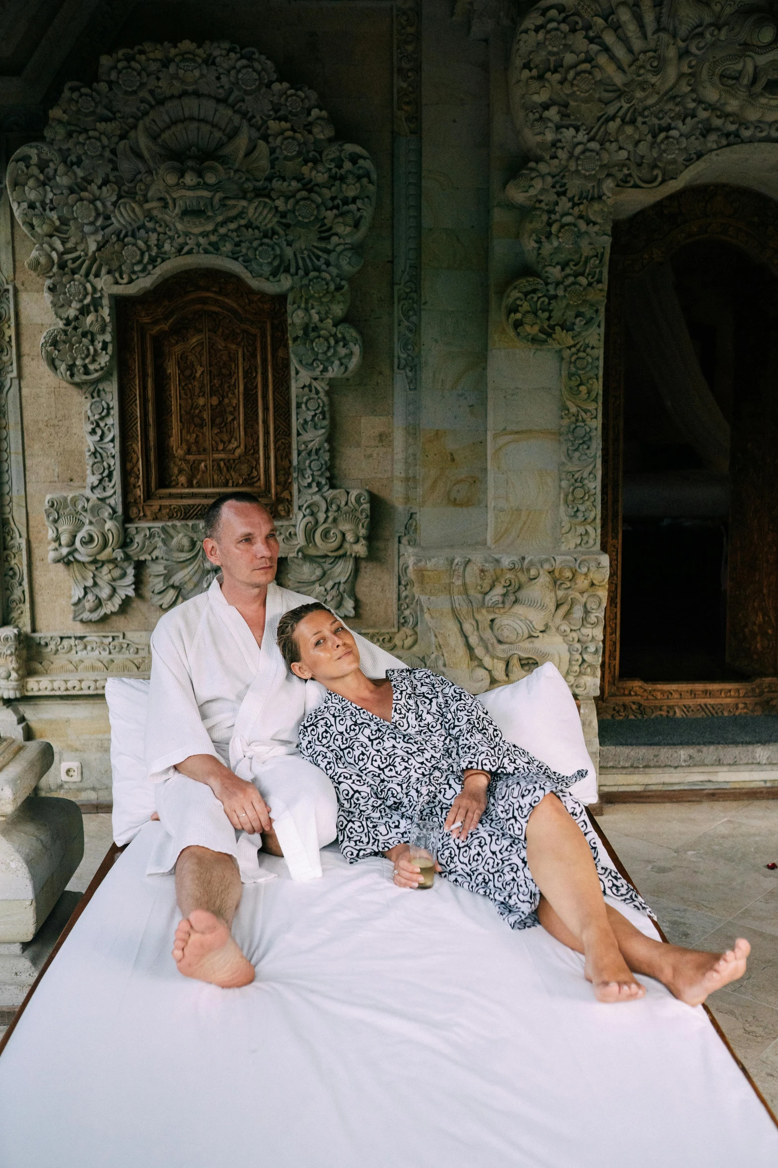 a couple in white sitting on the bed together