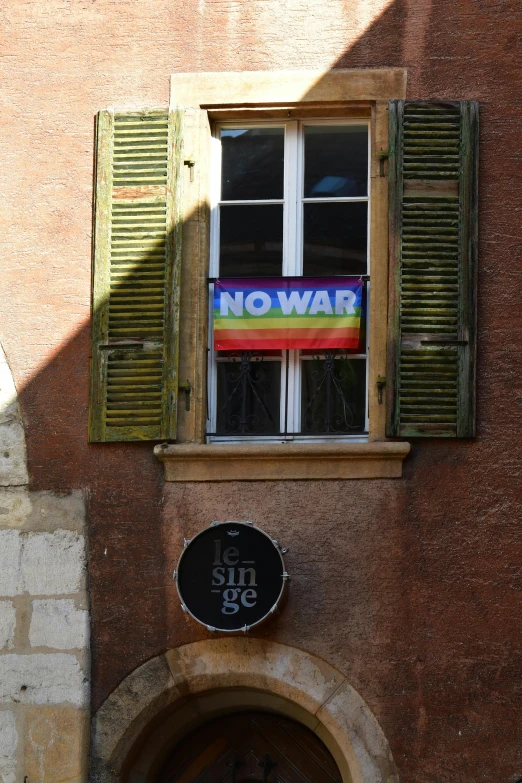 a sign reading no war hangs in the window of an old building