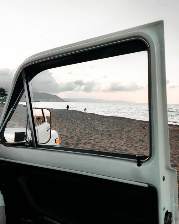 a car is parked on the beach next to the ocean