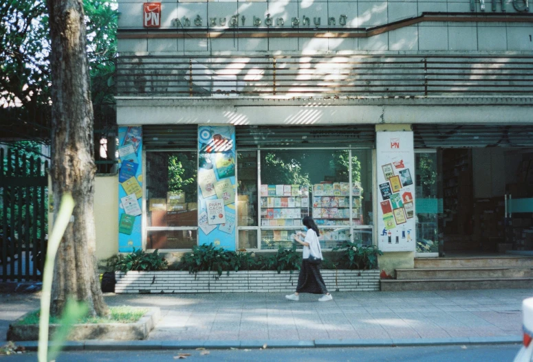 a woman is walking down a street past a storefront