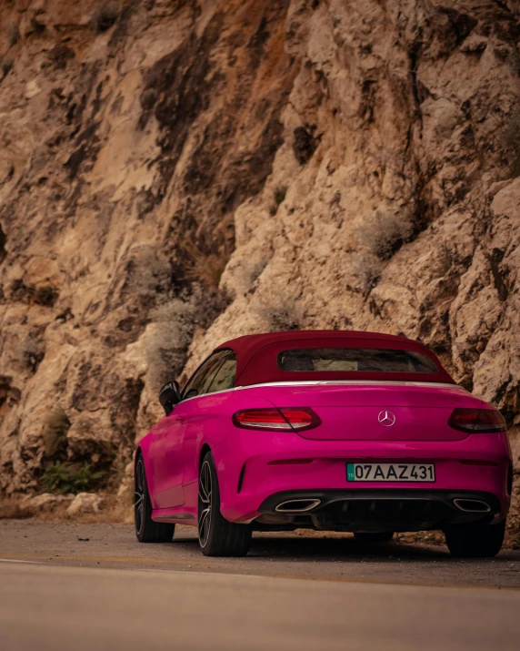 the red car is parked near the big rocks