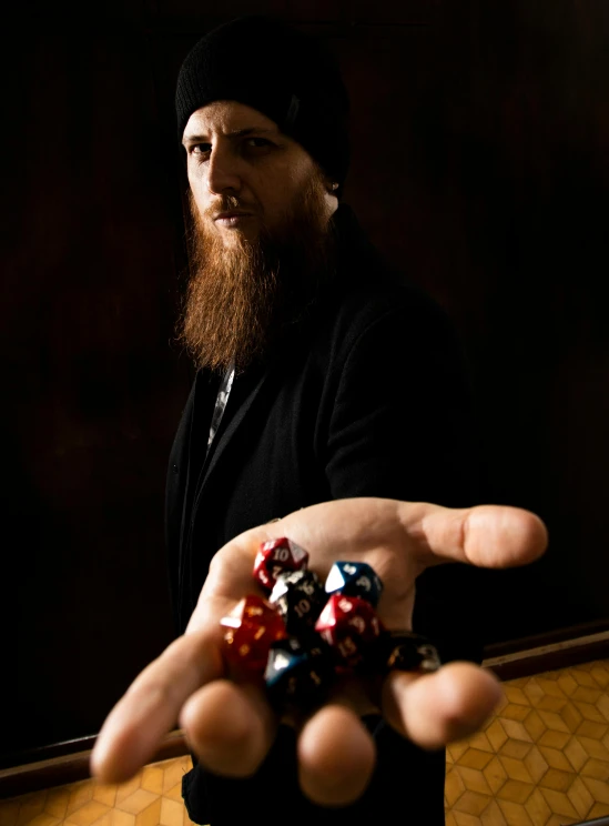 a bearded man holding several dices in his hands