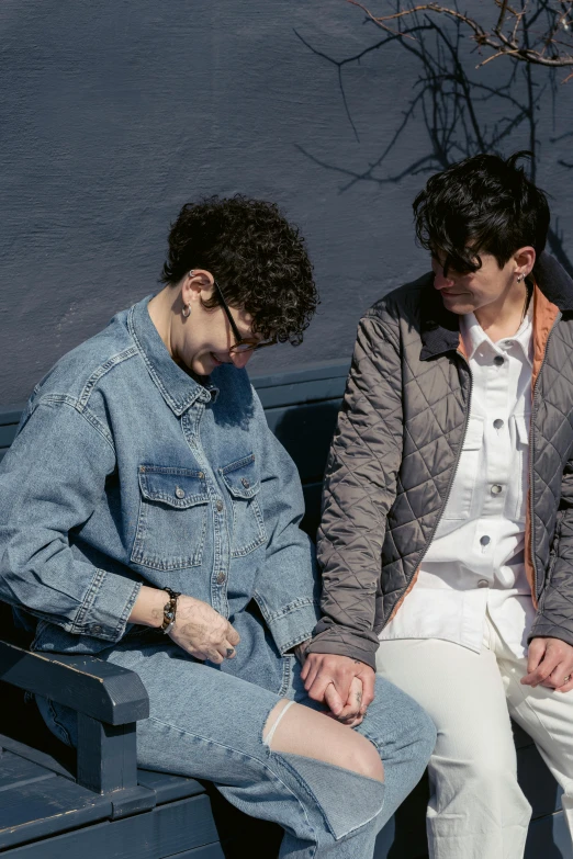 two young men sitting on the back of a blue bench