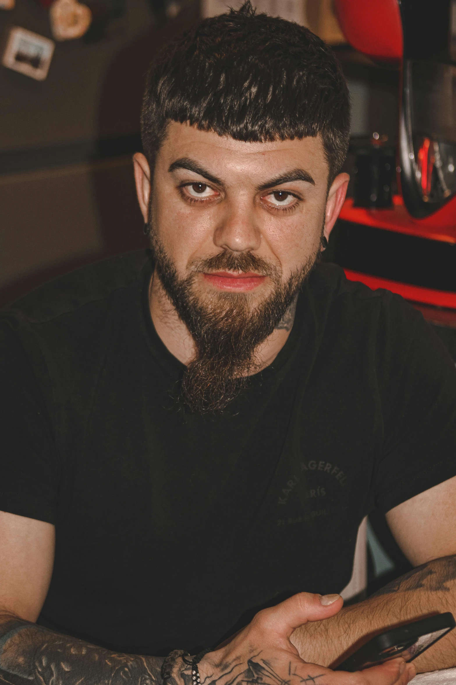 man in black shirt and tattoos on his arm looking at camera