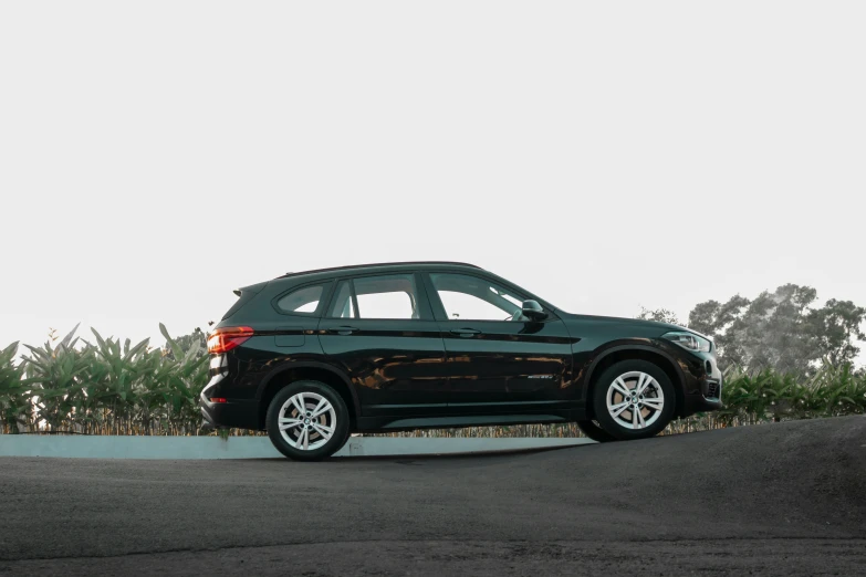 a black car is parked in front of a corn field