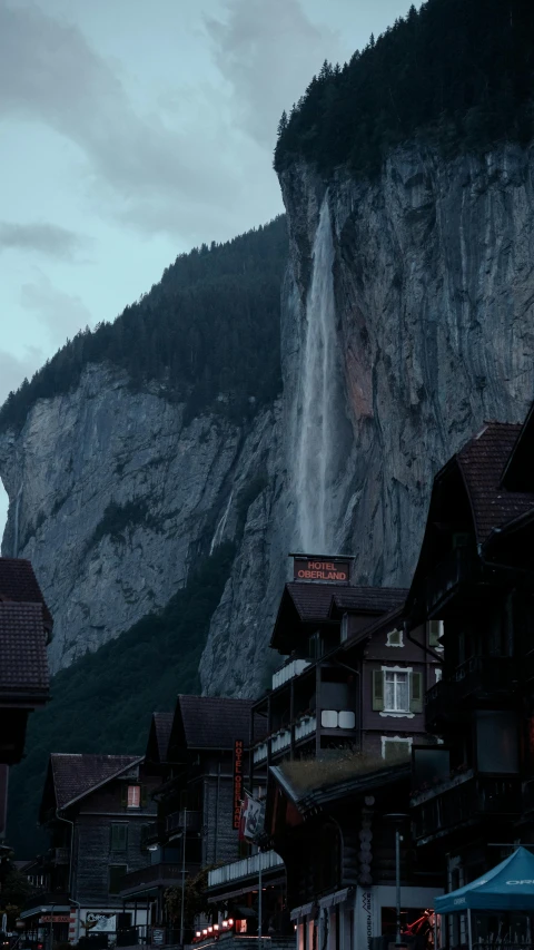 town with mountains and a waterfall at dusk