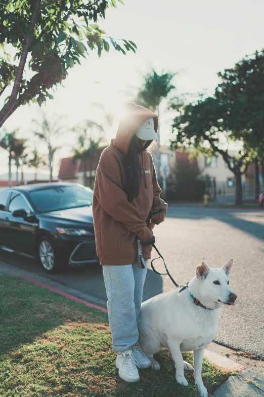 a person in brown hoodie standing next to dog on leash