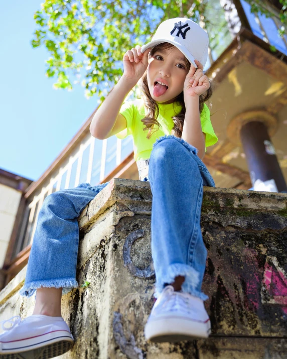 the girl is leaning up against a fence wearing a green shirt and hat