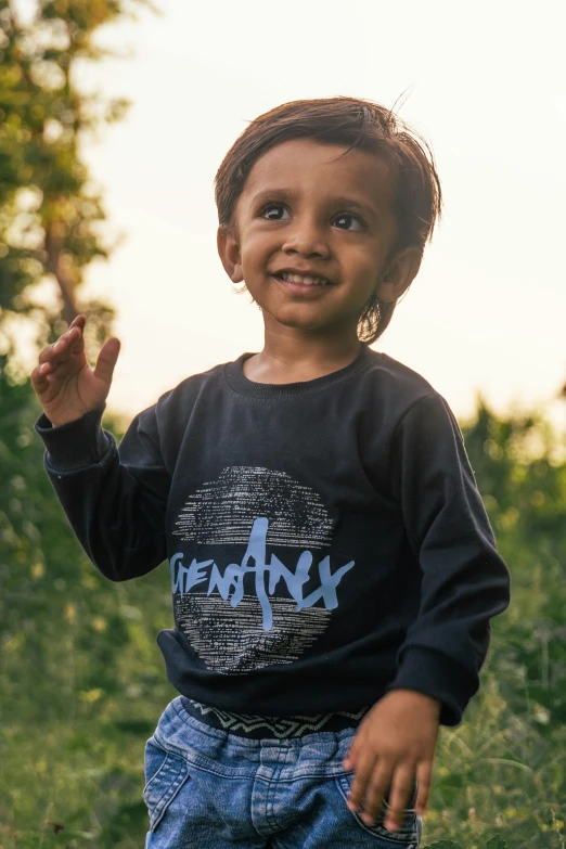 a small child standing in tall grass with his arm in the air