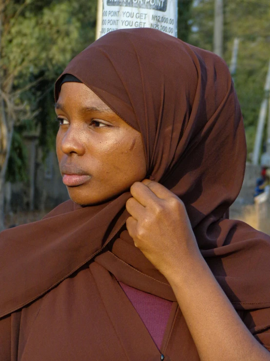 the woman is wearing brown clothing and posing for the camera