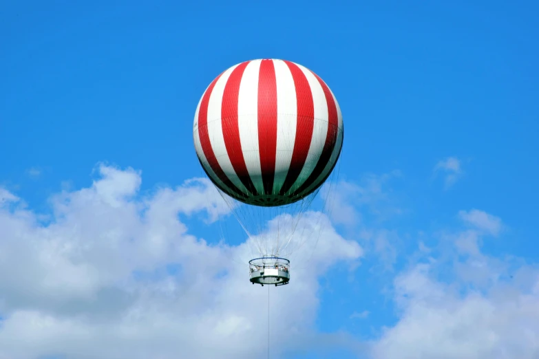 a large balloon with a parachute suspended in the sky