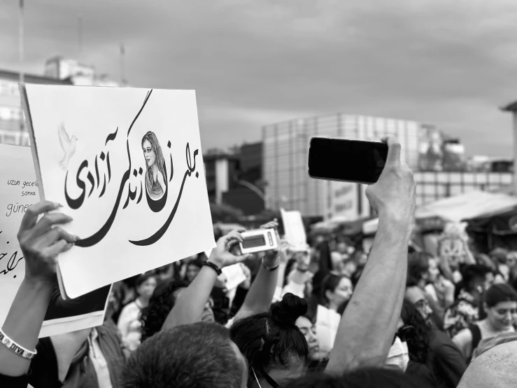 people in the crowd with arabic writing hold signs