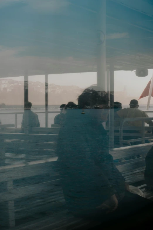 people sit on the pier with a city view through a glass window