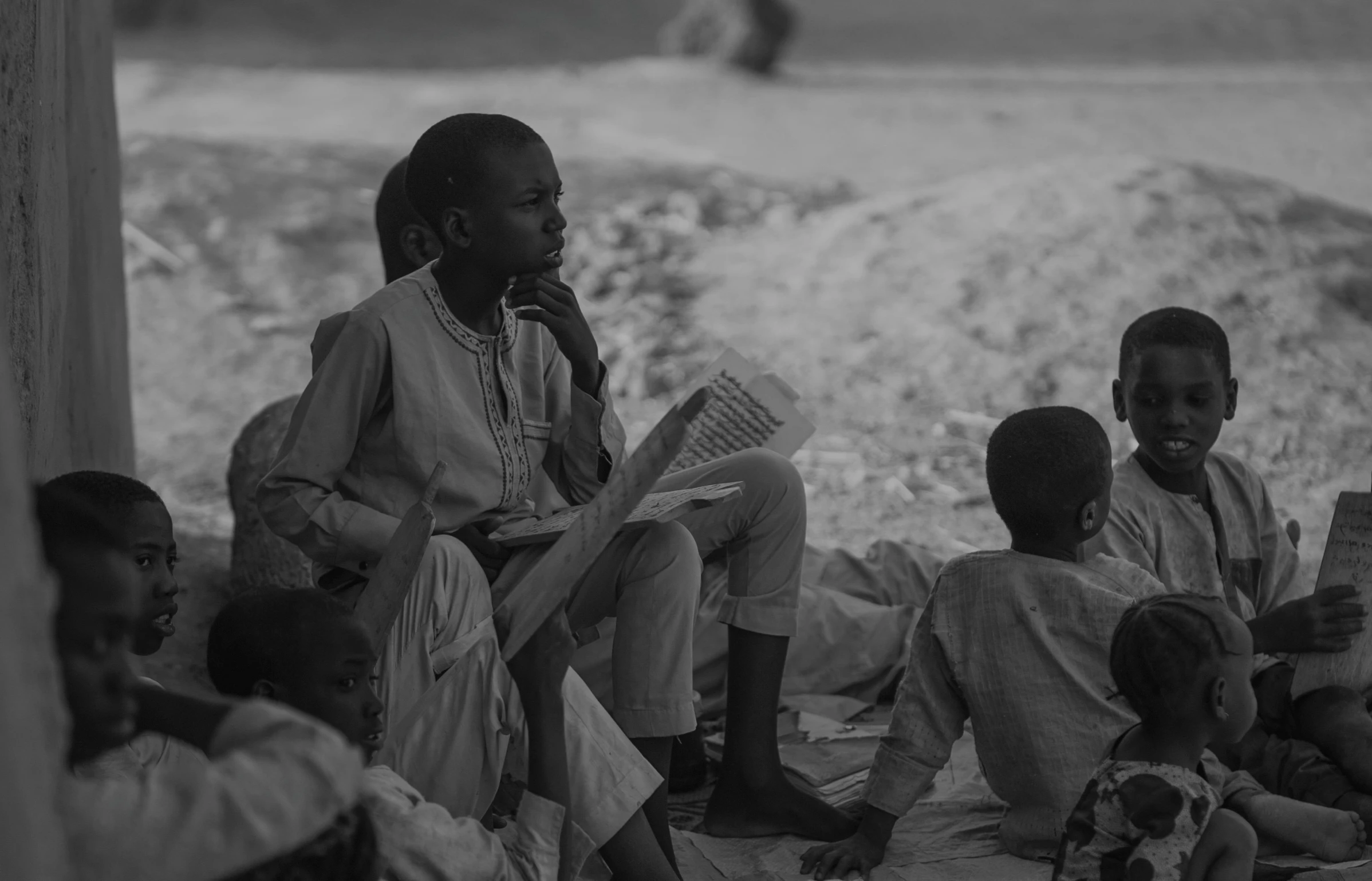 a woman reading a book with children in a village