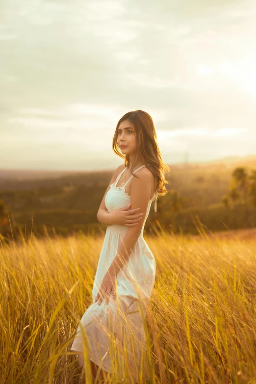 a beautiful woman in the middle of tall grass at sunset