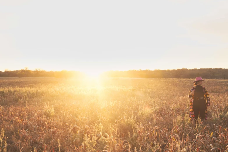 a woman standing on top of a field under a bright sun