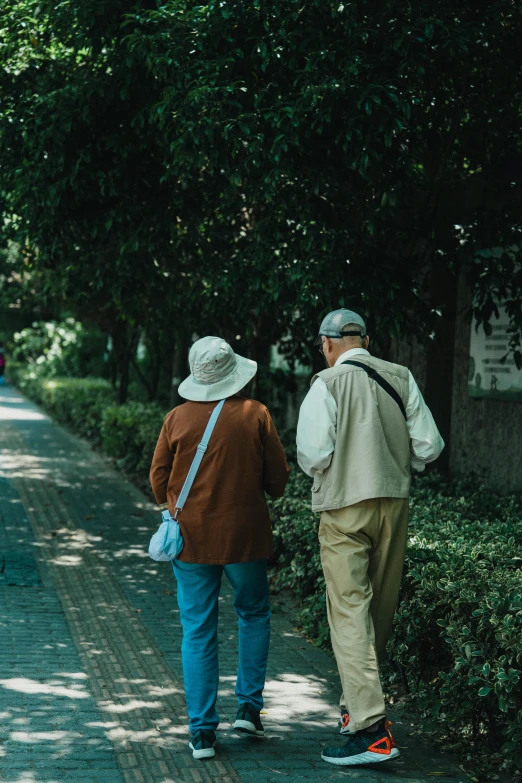 two people walking down a sidewalk near a forest