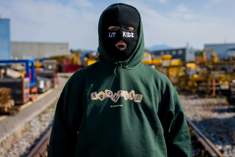 a hooded man standing on a train track