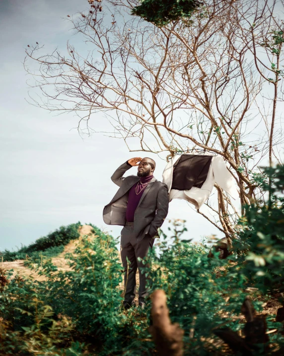 the man is standing in front of a tree with his head down and he has a black and white cow painted on it