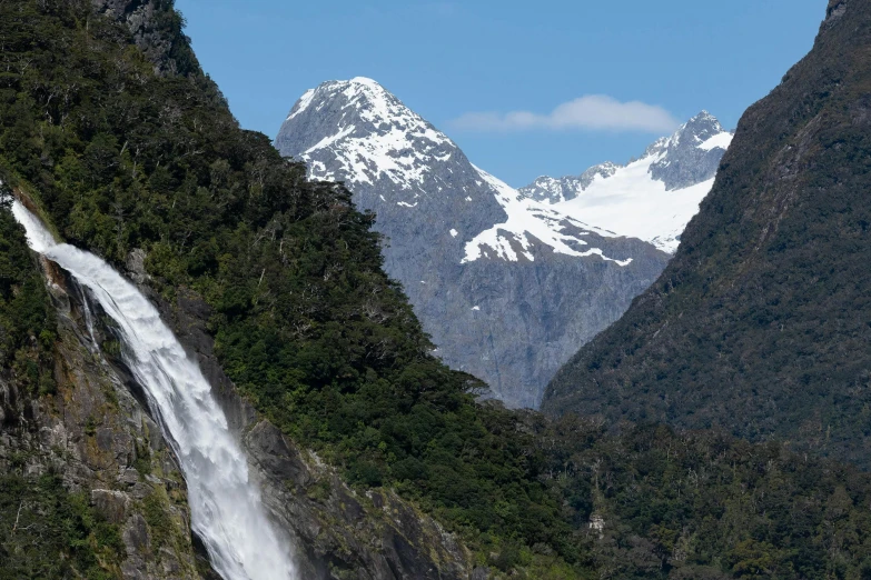 some snow capped mountains and a waterfall in the foreground