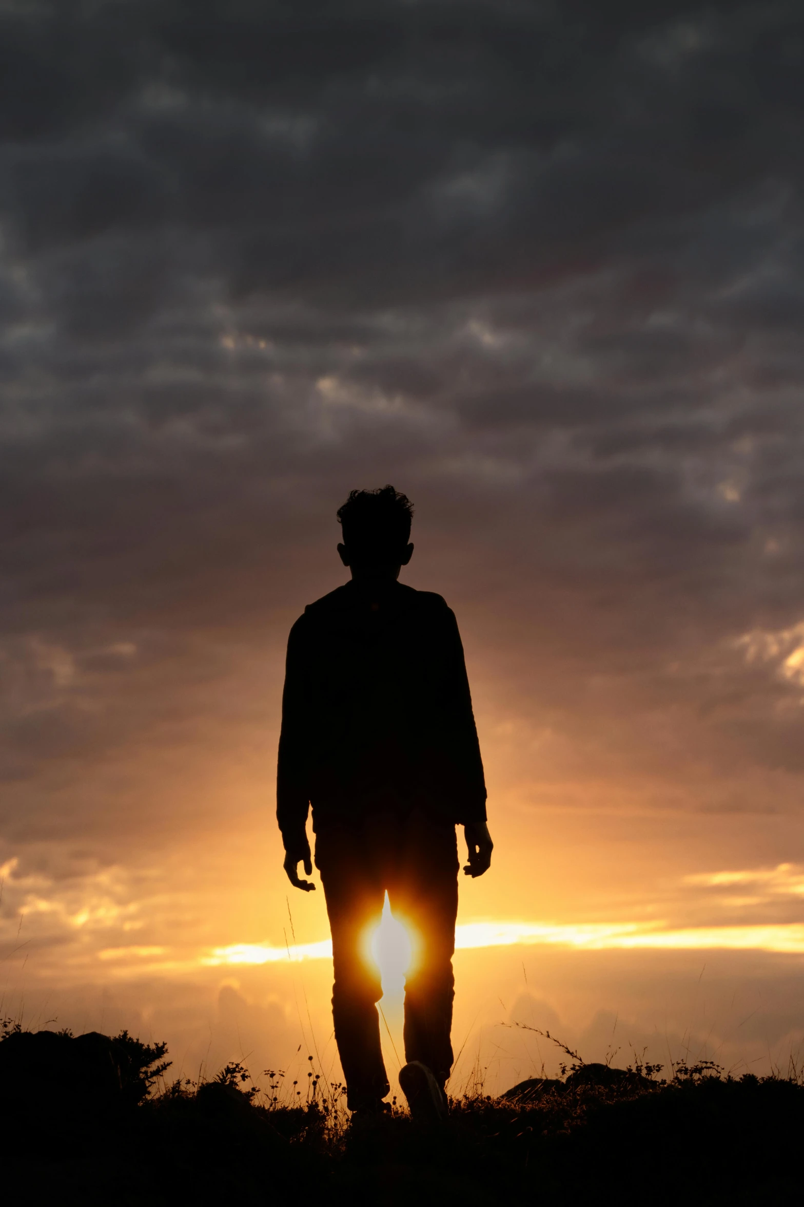 the silhouette of a man walking toward the sun