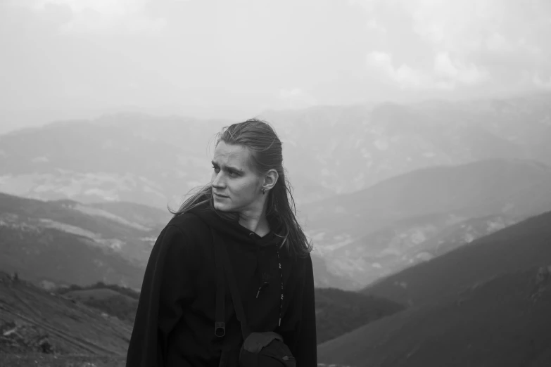 the woman stands alone in the fog on a mountain top