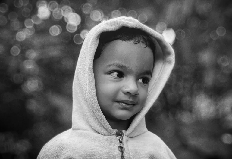 a black and white image of a boy in a hoodie