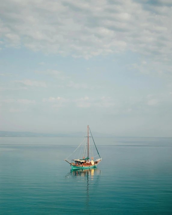 a small sail boat is sailing across the calm water