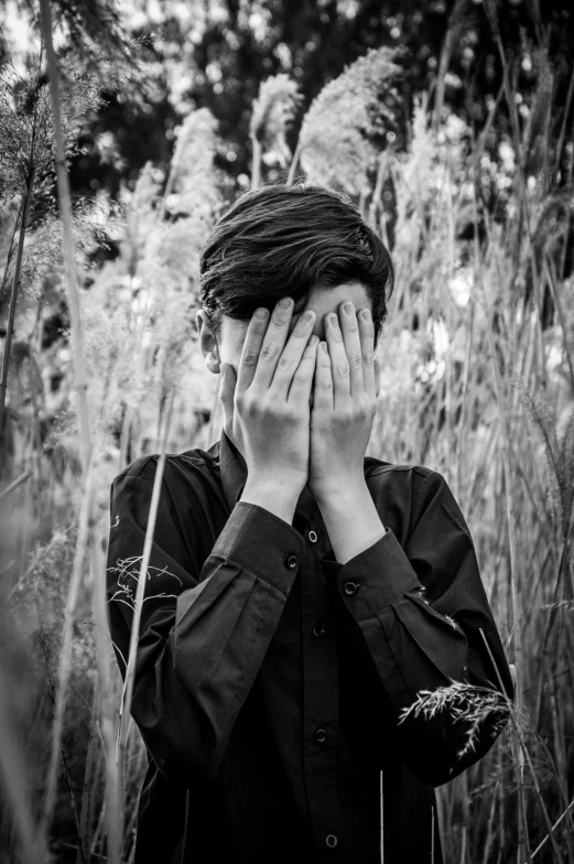 a person covers their eyes while walking through tall grass