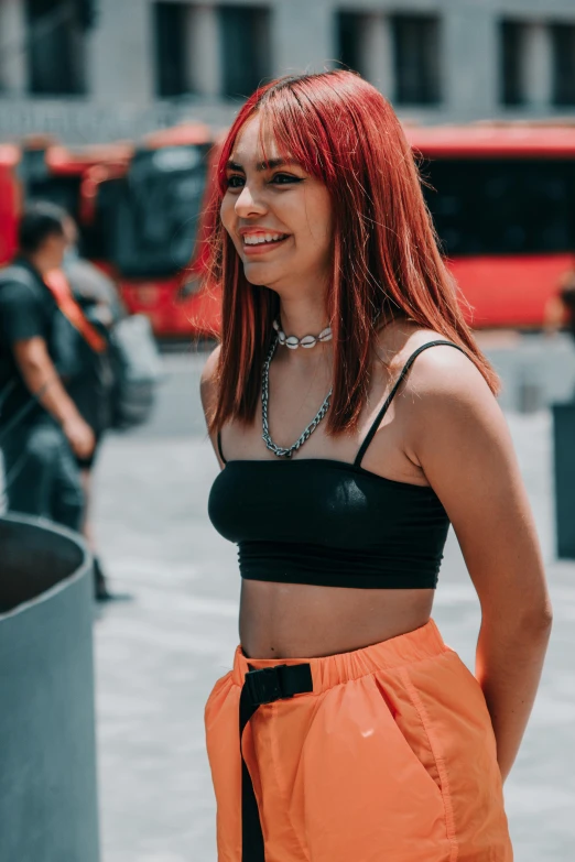 a woman with red hair is posing in a black and orange outfit