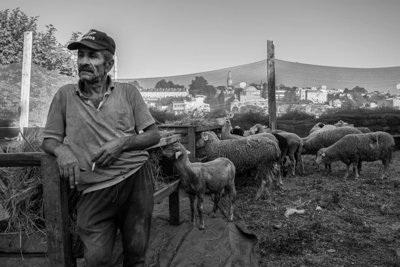 a black and white image of a man standing in front of sheep