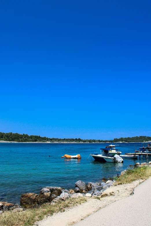 several boats are parked in the water and some people on the shore