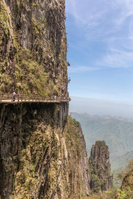 people are standing on a suspended bridge over a valley