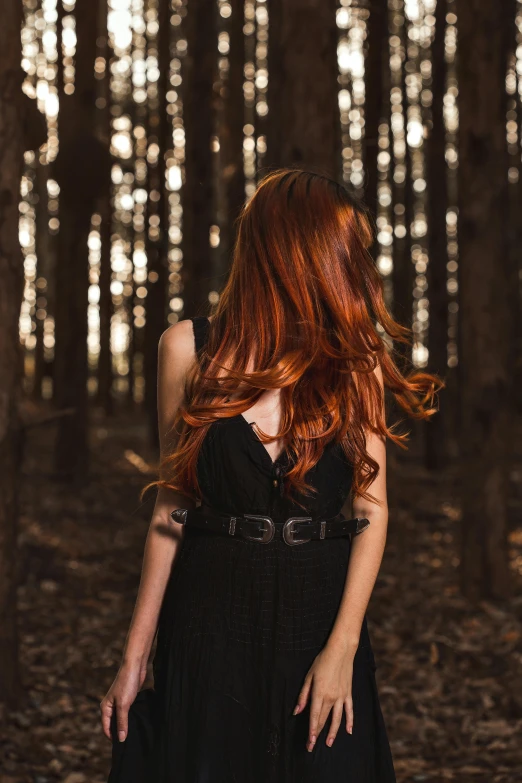 red haired woman with her hair blowing in the wind in a forest