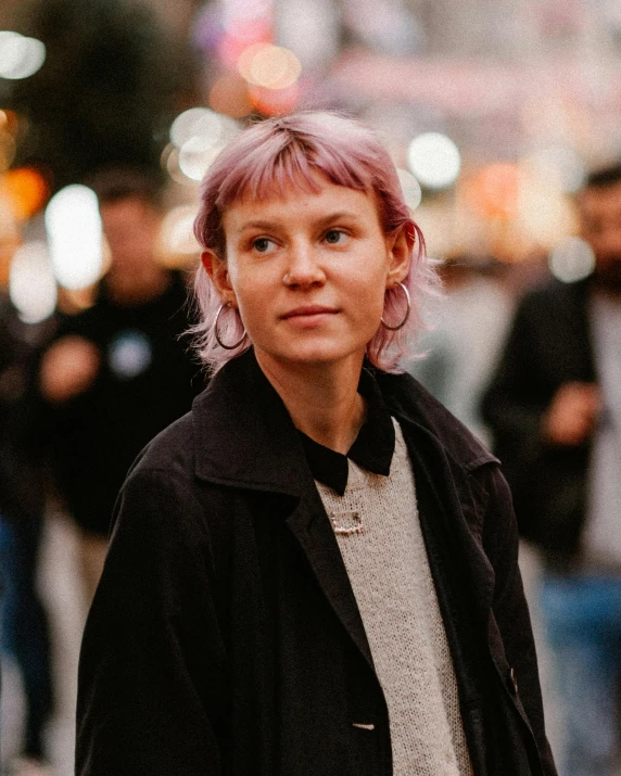 a man with pink hair and a jacket looks directly into the camera