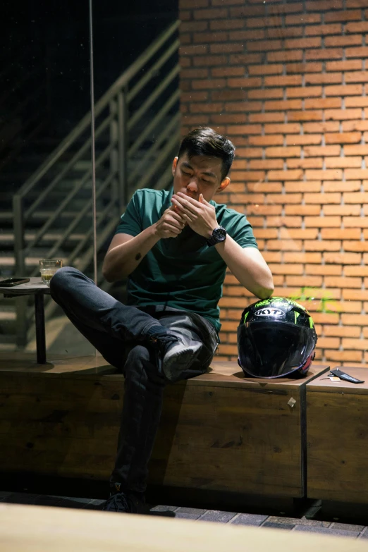 a man wearing a helmet sits on a ledge praying