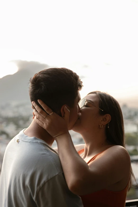 there is a man and woman kissing in front of a sky line