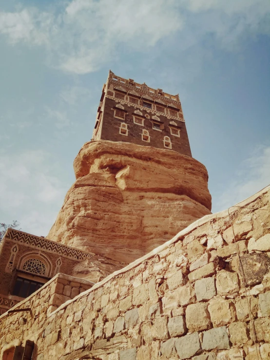 a tall brick building that is on top of a rock