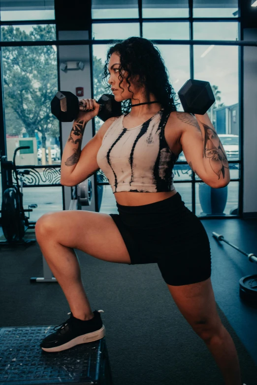 an attractive woman squats down while holding two dumbbells