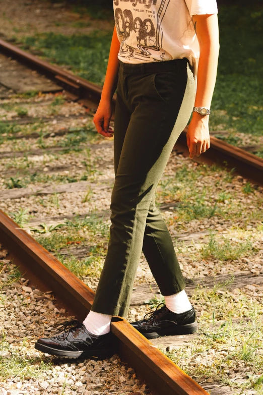 a young woman is standing on a railroad track with her hands in the pockets