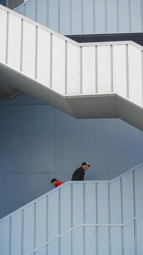 a man standing on the outside of a building with a man walking down it