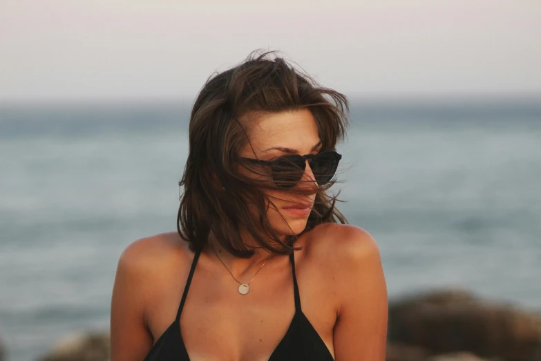 a woman is standing near the water in her bikini