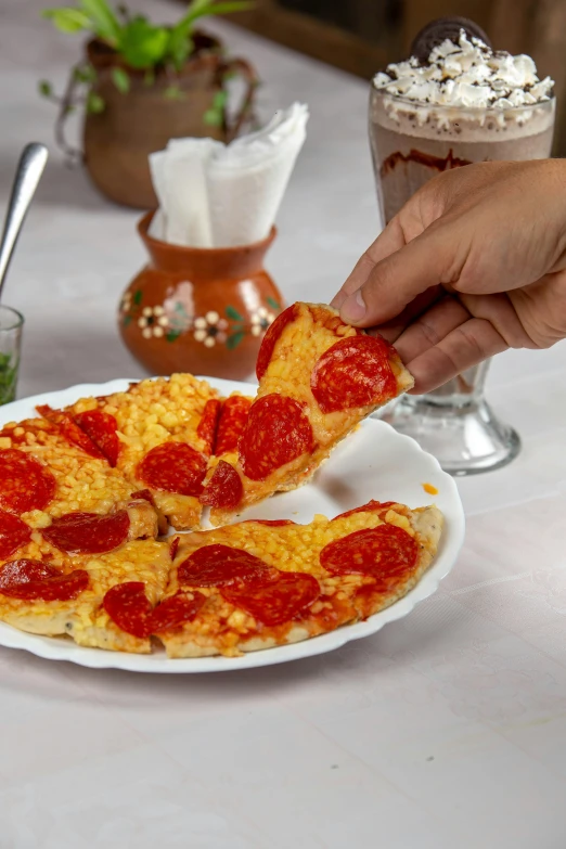 a person cuts into a pepperoni pizza at a table