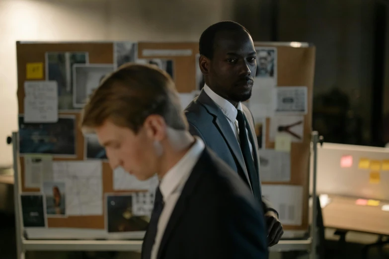 two men in suits walking around an office