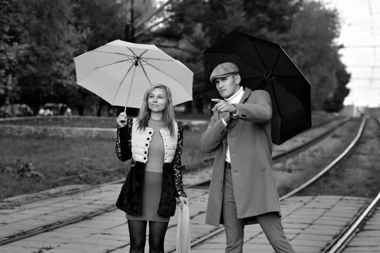 man with umbrella on a railway platform and a woman walking away