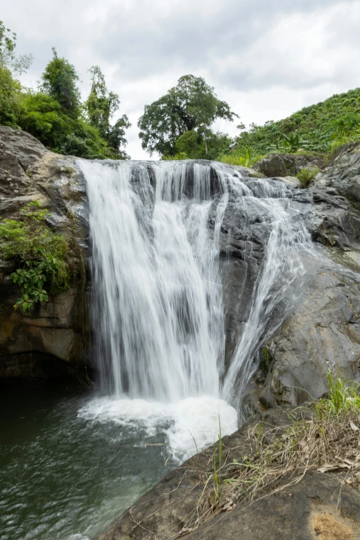 a waterfall is running into the water from the rocky ground