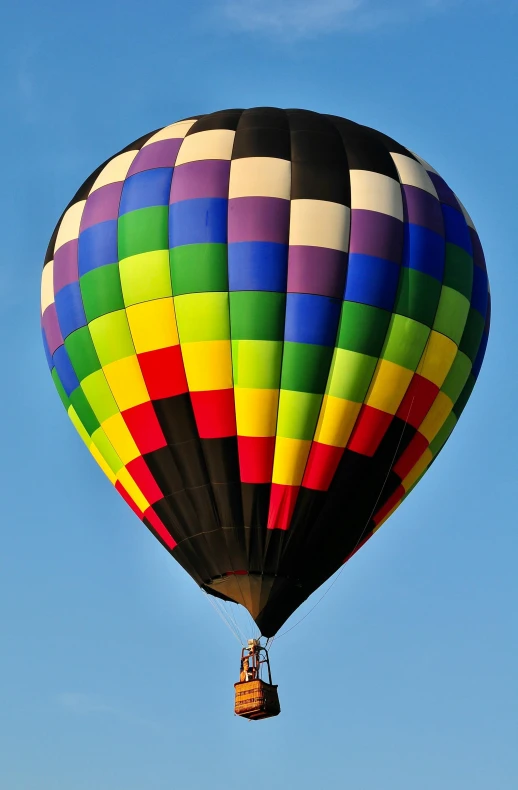 a rainbow colored  air balloon in the blue sky