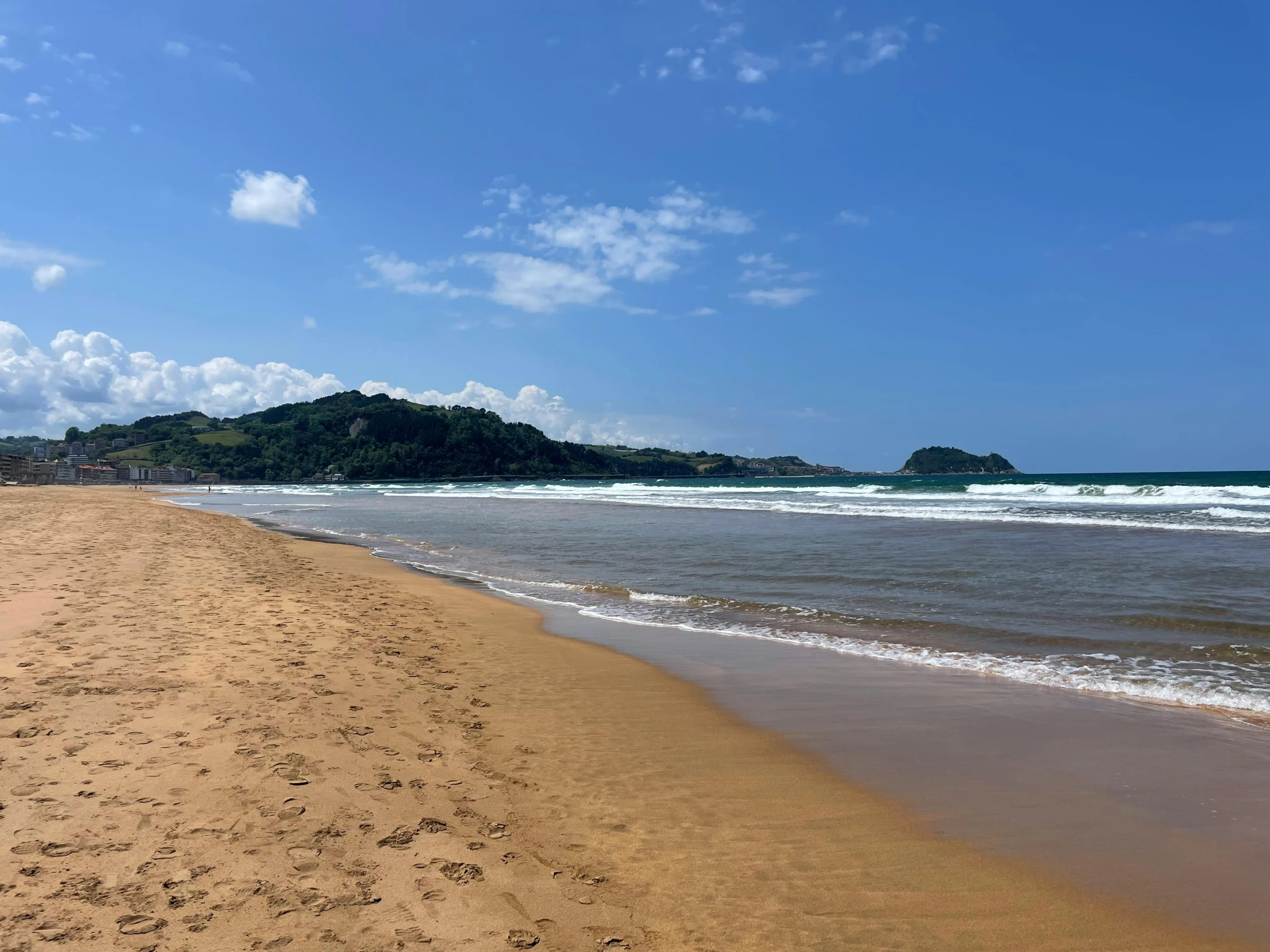 a sandy beach on an ocean shore under a blue sky